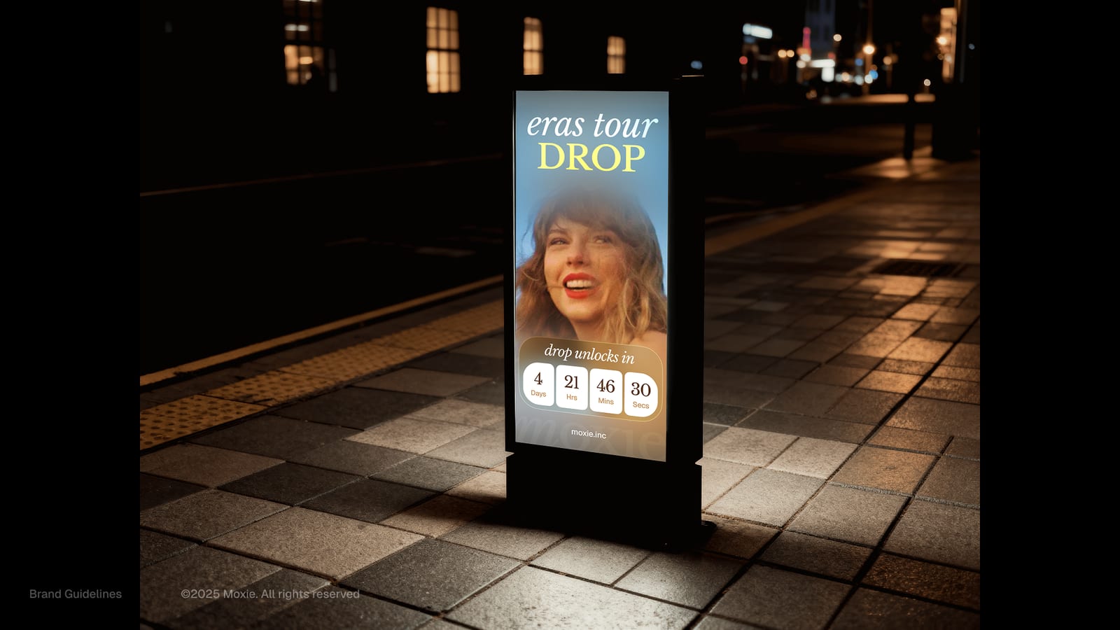 A night-time Moxie digital poster for an 'eras tour' drop on a city street
